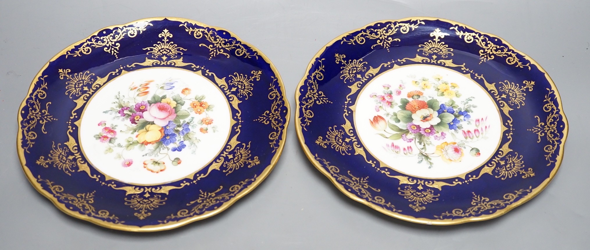 A pair of Coalport floral plates with cobalt blue borders having raised and flat gilding, both by Frank Howard, signed F. Howard, made for Waring and Gillows, Crown England mark